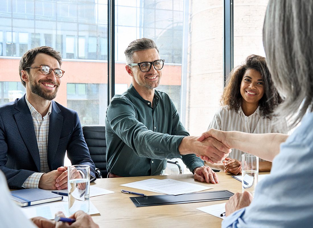 Contact - Friendly Group of Business People Shake Hands at an Office