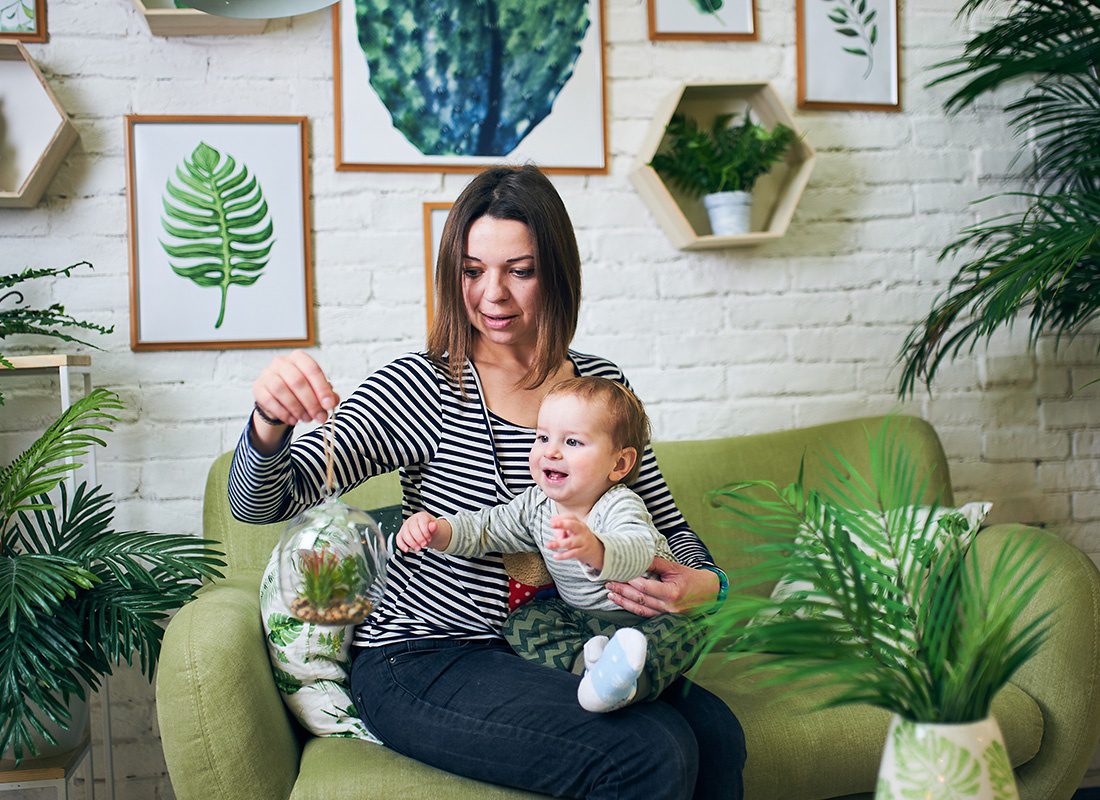 Personal Insurance - Mother and Baby Sit Together in a Living Room Full of Plants
